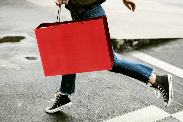 Person carrying red shopping bag crossing the street near St. Simons Island shops