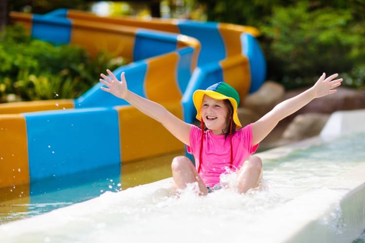 Girl holding hands out on water slide wearing a bucket hat